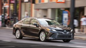 Moving shot of a 2019 Toyota Camry sedan driving in a city