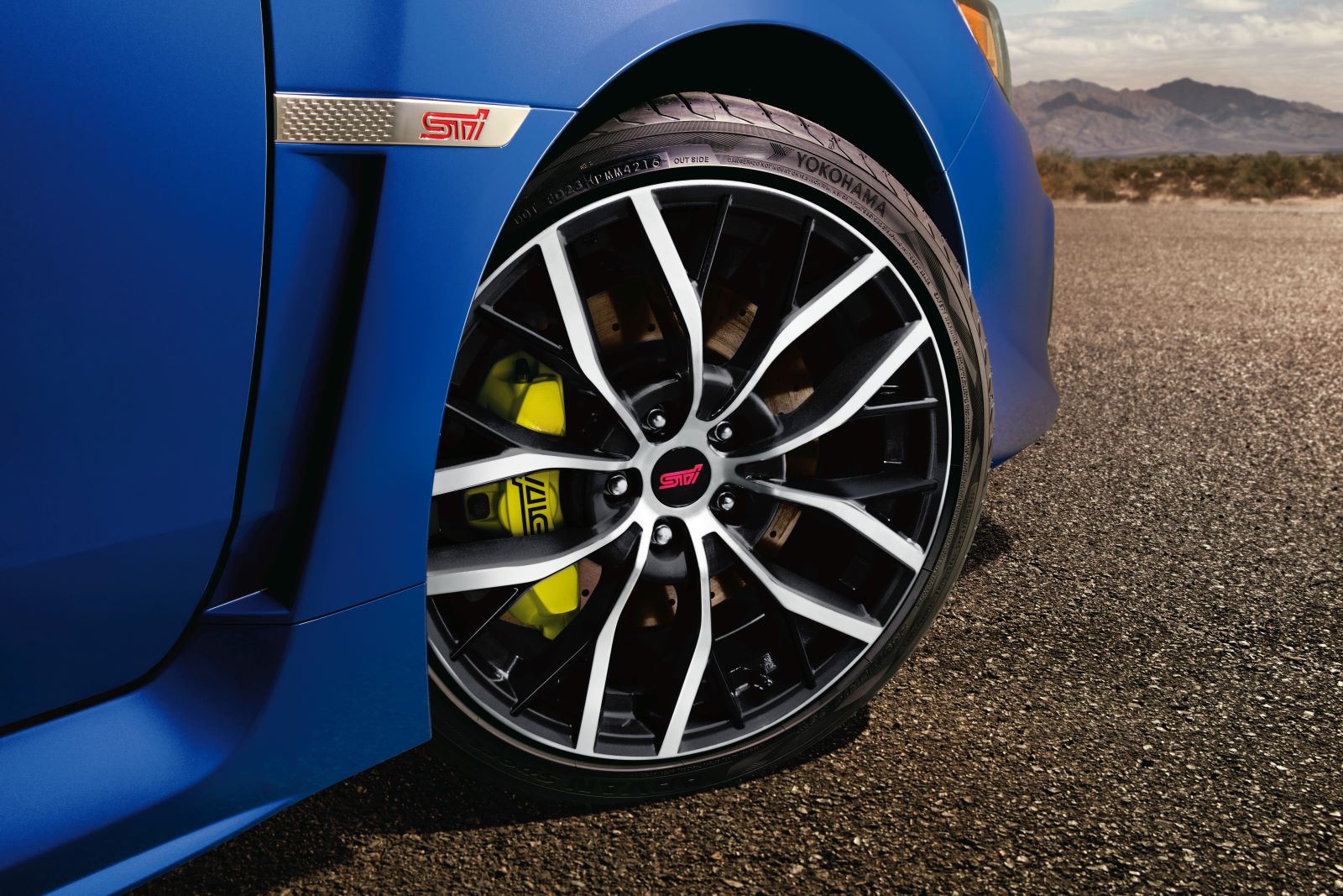 Close-up on the front right wheel of a blue 2020 Subaru WRX STI parked on asphalt