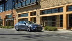 The 2021 Chevrolet Malibu midsized sedan parked outside a wood and brick building