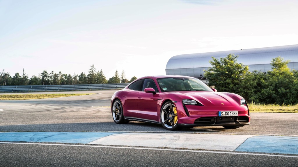 The 2021 Porsche Taycan Turbo S in pink parked at the edge of a racetrack