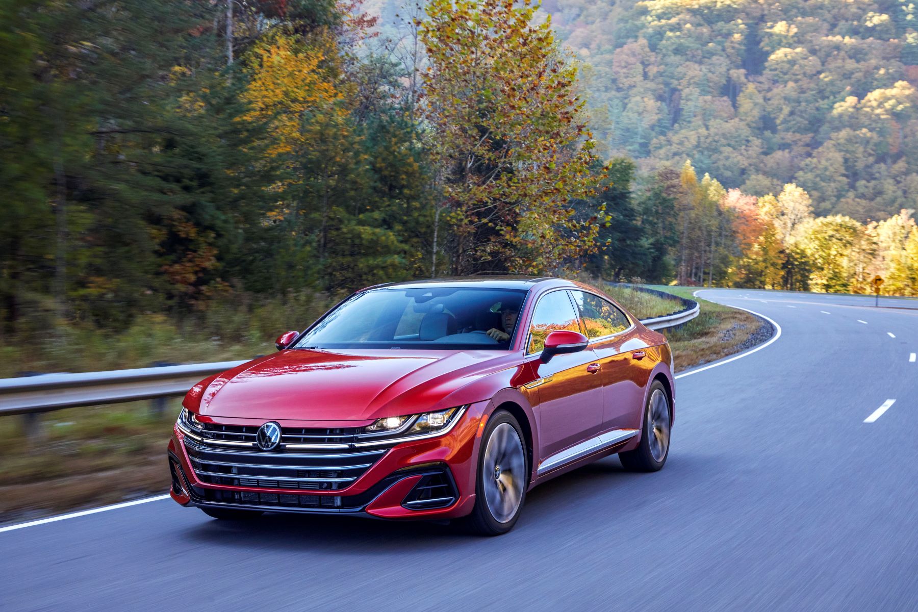 2021 Volkswagen Arteon compact executive liftback shooting brake sports sedan in red driving on a forest highway