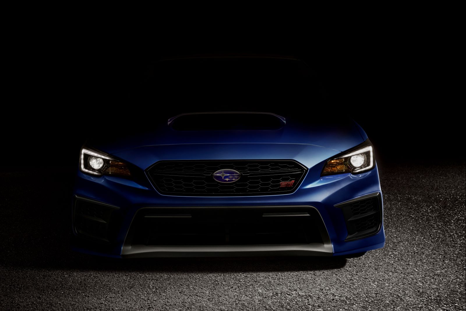 Dark front view of a 2020 Subaru WRX STI in blue. Only the front end and headlights of the car are visible