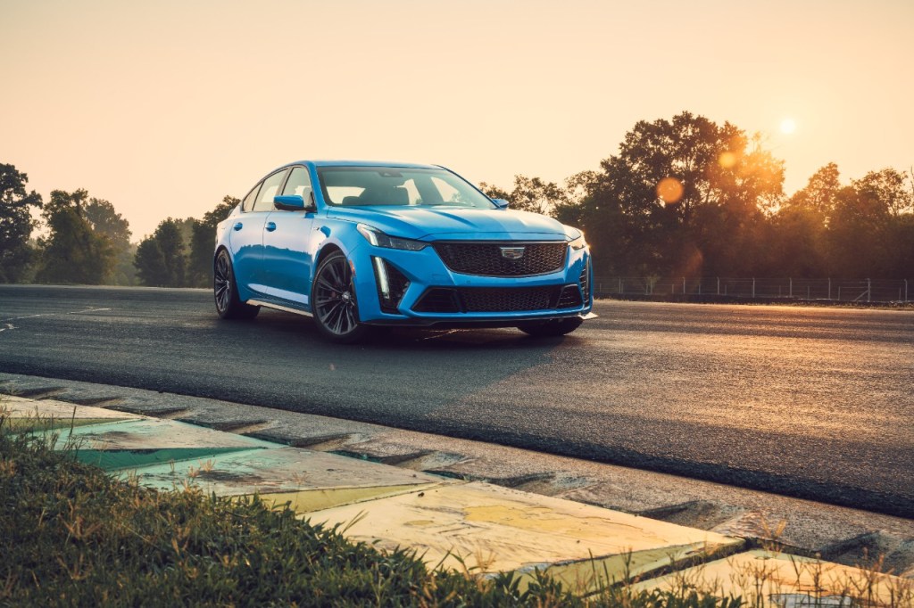 Front view of a blue 2022 Cadillac CT5-V Blackwing sports sedan parked on a tarmac road at sunset