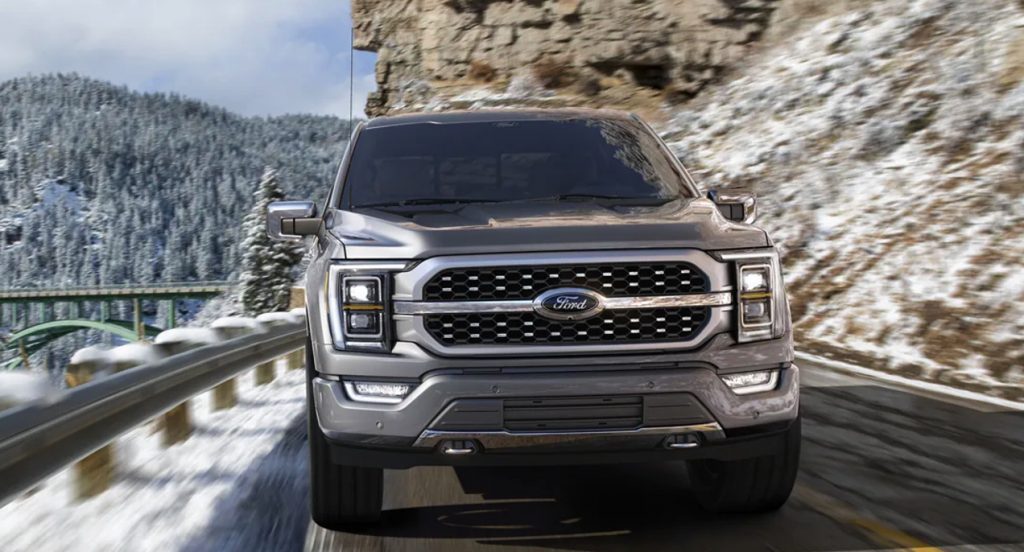 A gray 2022 Ford F-150 pickup truck is driving on the road. 