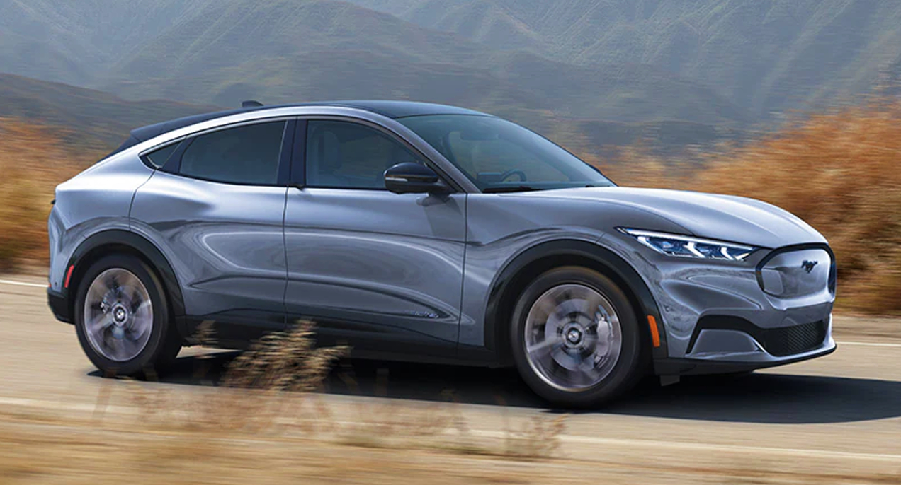 A gray 2022 Ford Mustang Mach-E electric SUV is driving on the road.