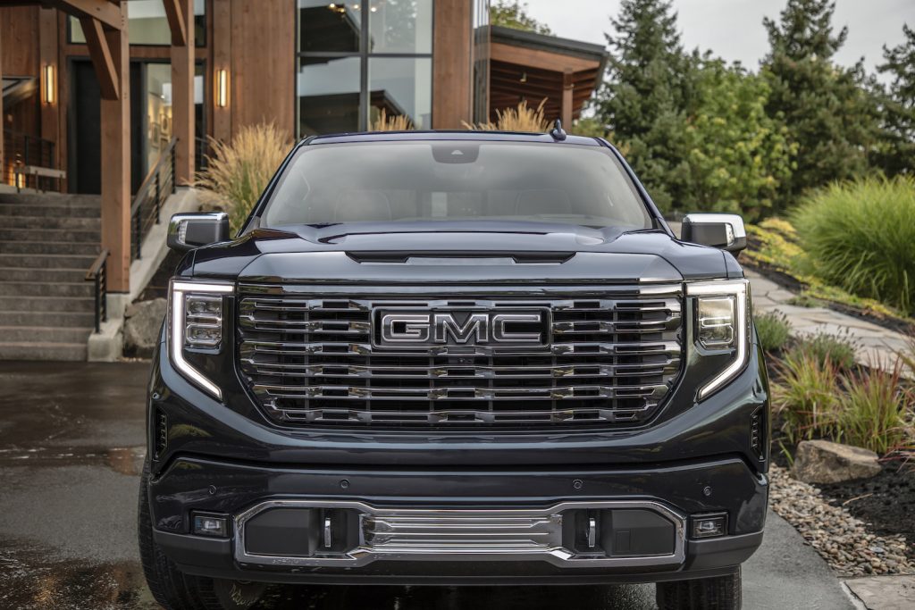 Promotional image of a GMC logo in the grille of a Sierra pickup.