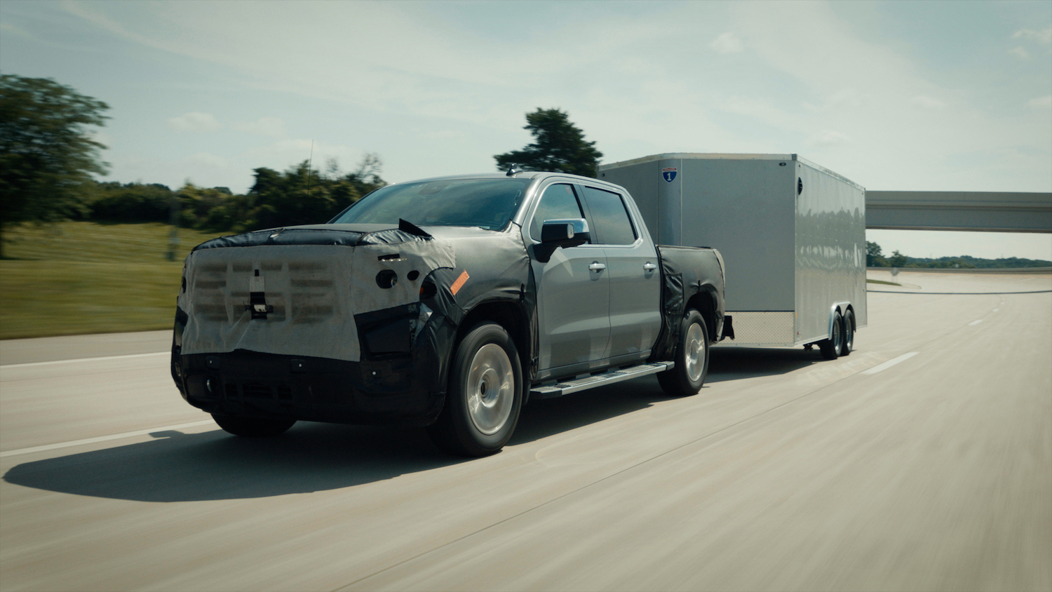 Gray, self driving truck towing a trailer without driver input.