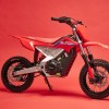 A red-white-and-blue 2022 Honda CRF-E2 electric dirt bike on its kick-stand