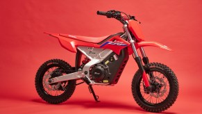 A red-white-and-blue 2022 Honda CRF-E2 electric dirt bike on its kick-stand