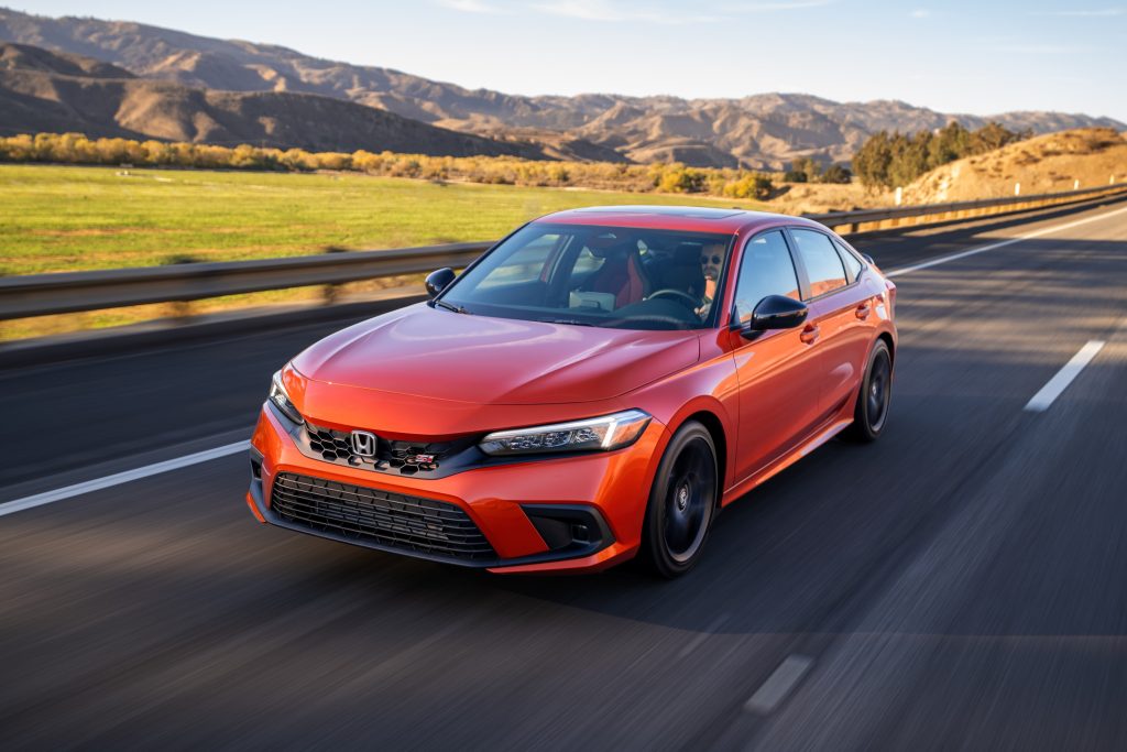 An orange 2022 Honda Civic Si drives down a country road