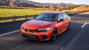 An orange 2022 Honda Civic Si drives down a country road