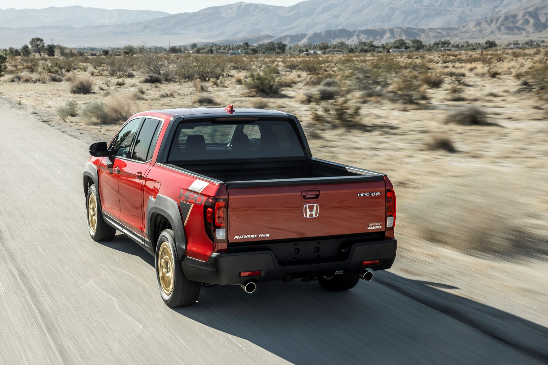 2022 Honda Ridgeline Sport with HPD package unibody pickup truck in red driving down a desert highway