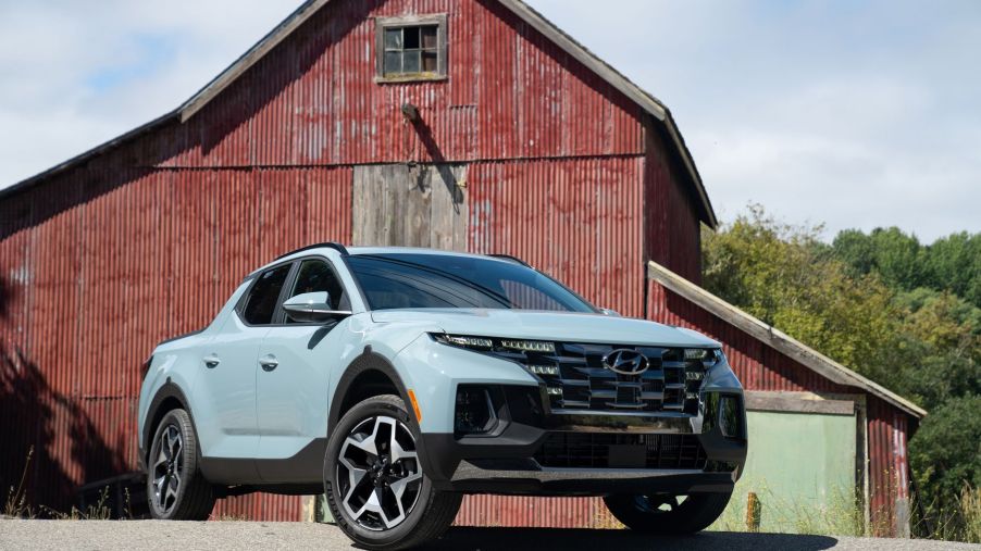 2022 Hyundai Santa Cruz compact pickup truck in light blue parked in front of a steel barn