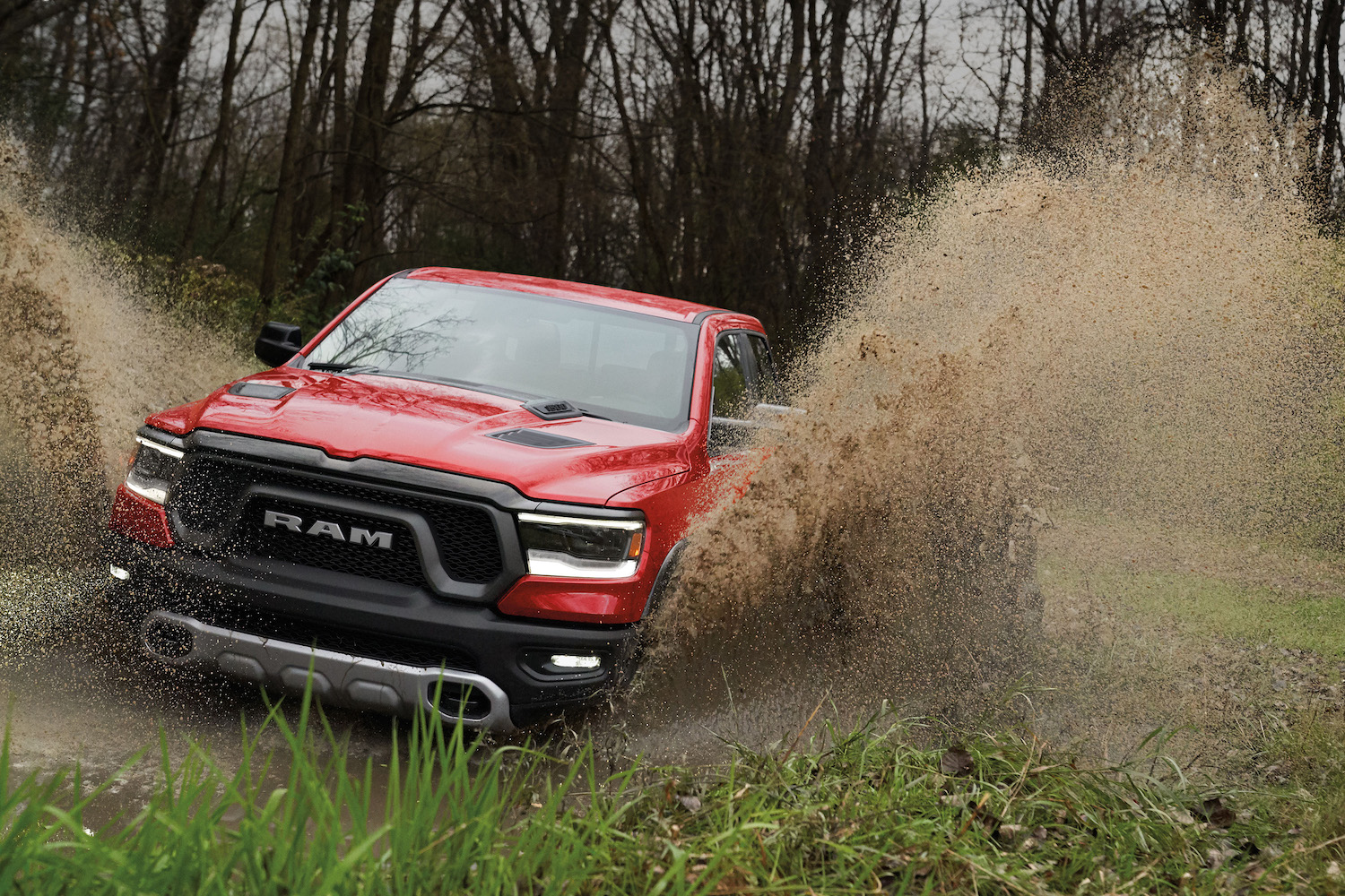 Red Ram rebel pickup truck driving through a swamp, fishtails of water erupting from each wheel well.