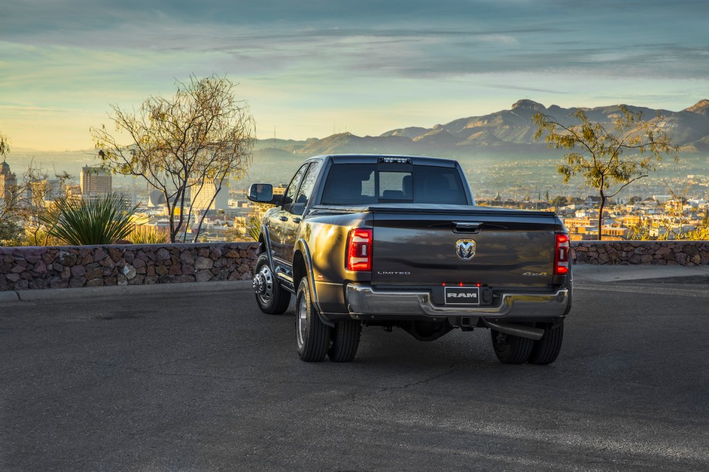 The bed of a heavy duty Ram 3500 truck in a parking lot, facing a city skyline, its dual rear wheels visible.