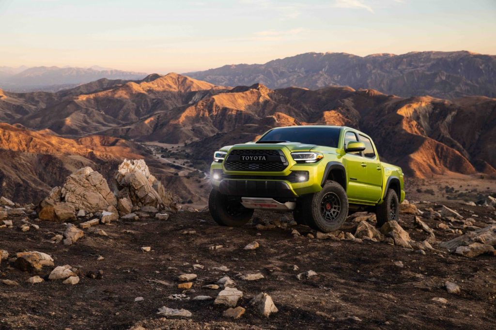 Lime green Toyota Tacoma parked in the desert with a mountain range in the distance.