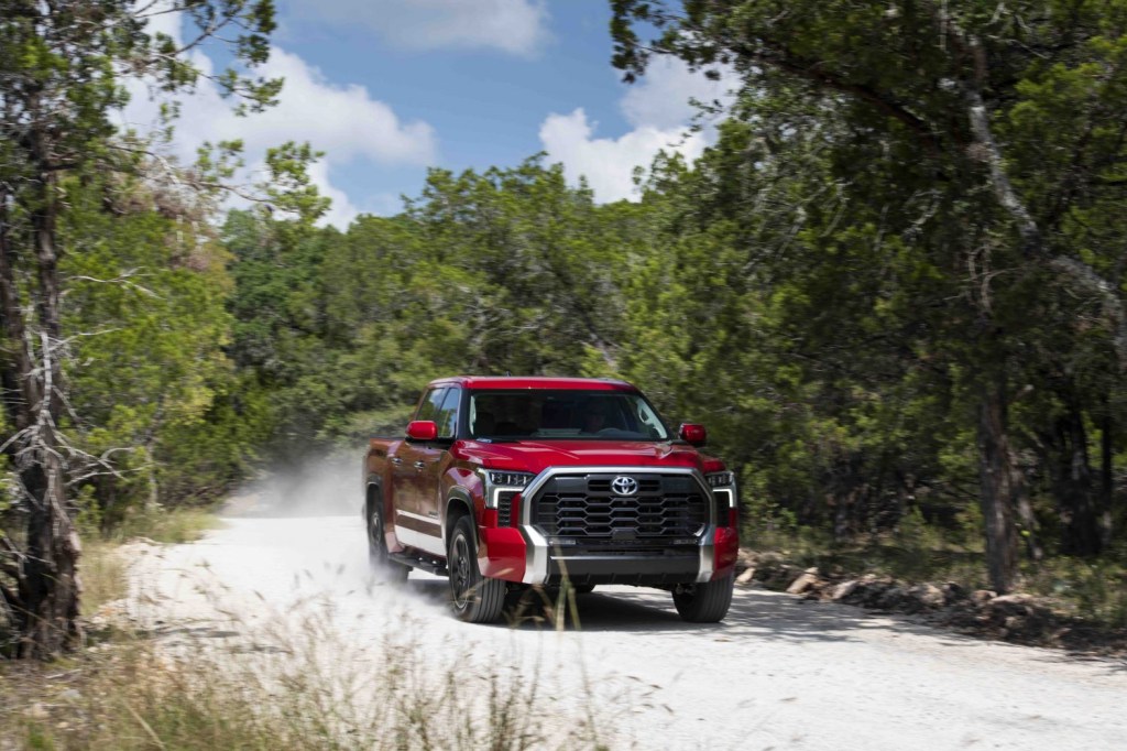 Toyota Tundra with TRD Off-Road package speeding along a dirt road with a cloud of dust in the background.
