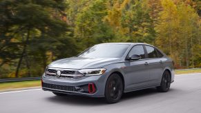 A gray 2022 Volkswagen Jetta GLI driving down a forest road