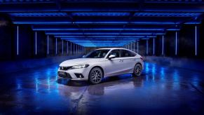 White 2022 Honda Civic e:HEV Hybrid sedan set against a dramatic dark-blue backdrop