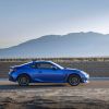 Side profile of a blue 2022 Subaru BRZ coupe, trim level uncertain, parked on a dirt road against the backdrop of sprawling mountains