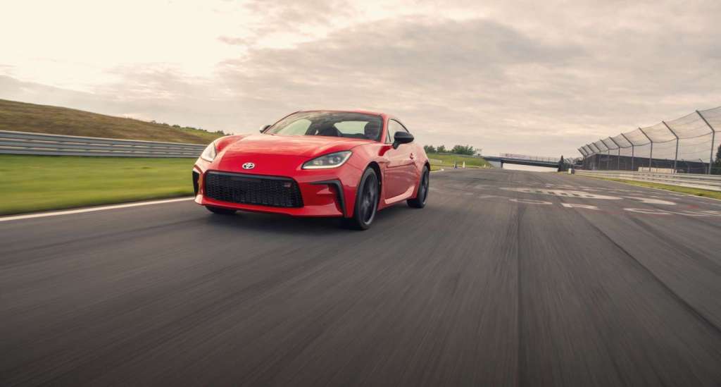 Red 2022 Toyota GR86 sports car driving towards the camera on a track