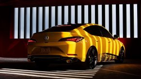 The rear 3/4 view of the yellow 2023 Acura Integra Prototype in a garage