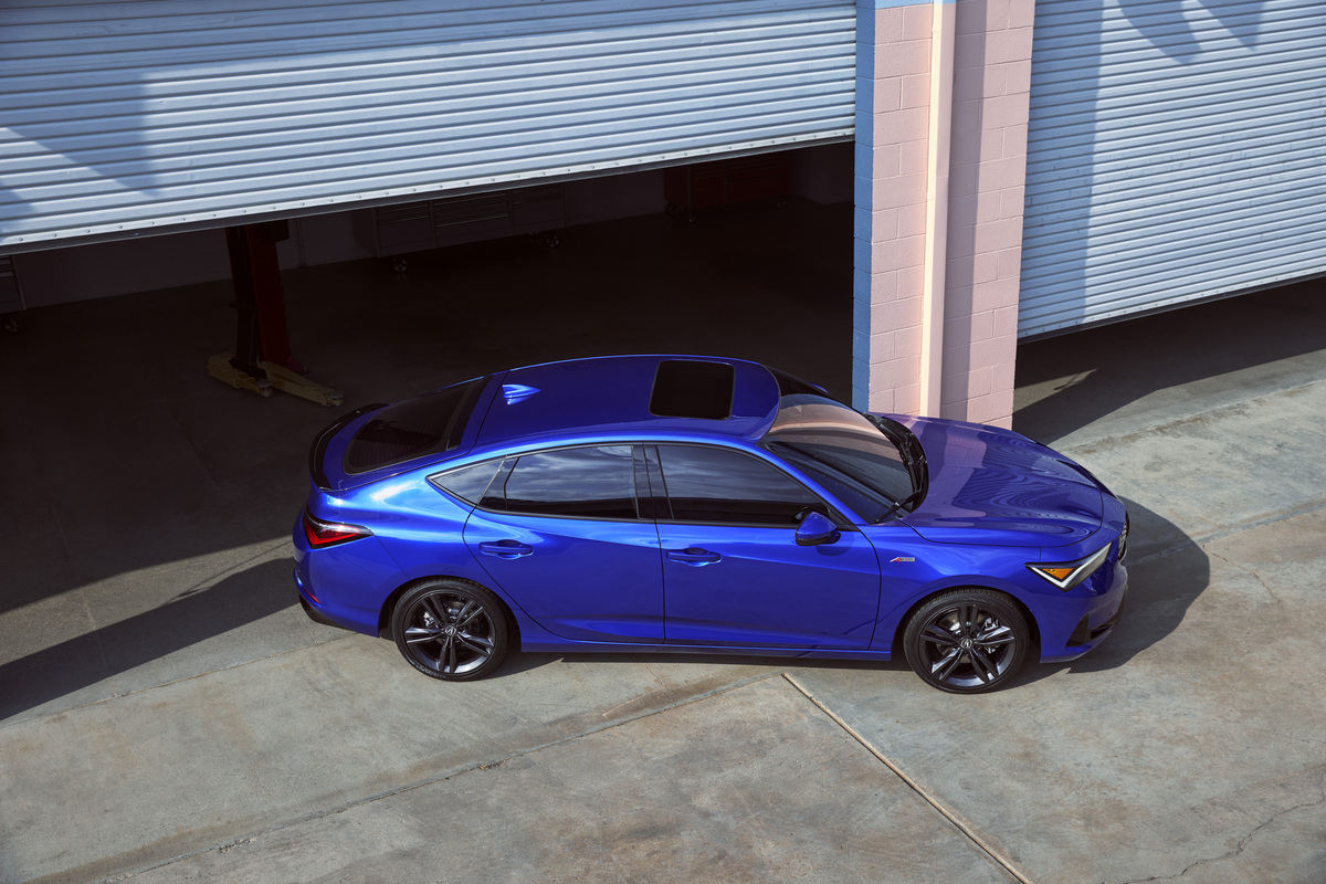 Blue 2023 Acura Integra liftback sports car parked directly outside of a high-end garage