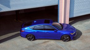 Blue 2023 Acura Integra liftback sports car parked directly outside of a high-end garage