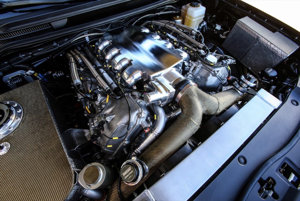 Toyota engine bay with a twin-turbocharged V8 tuned racing engine visible.