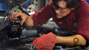 A red-clothed mechanic replaces the oil filter on a 1985 Mercedes-Benz