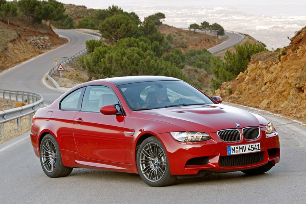 A red 2010 E92 BMW M3 Coupe parked by a twisty canyon road