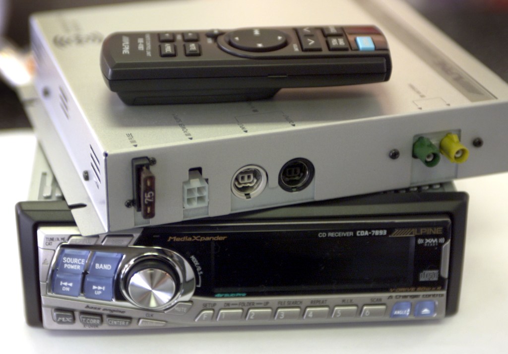 The Alpine TUAT020XM XM radio tuner module with remote control, shown on top, and the XMready Alpi