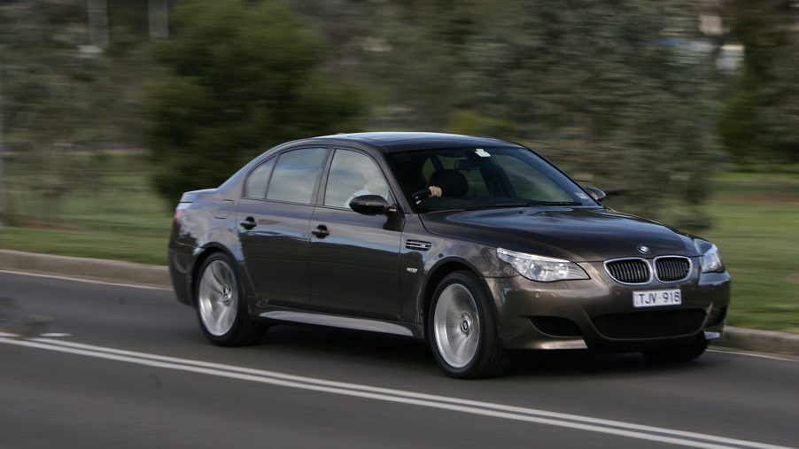 A brown 2005 E60 BMW M5 sports car driving down the road at speed