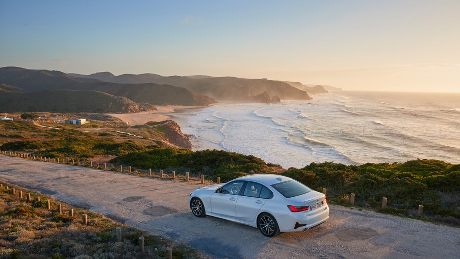 BMW 3 Series on beach coastal highway with sunset in the bakcground