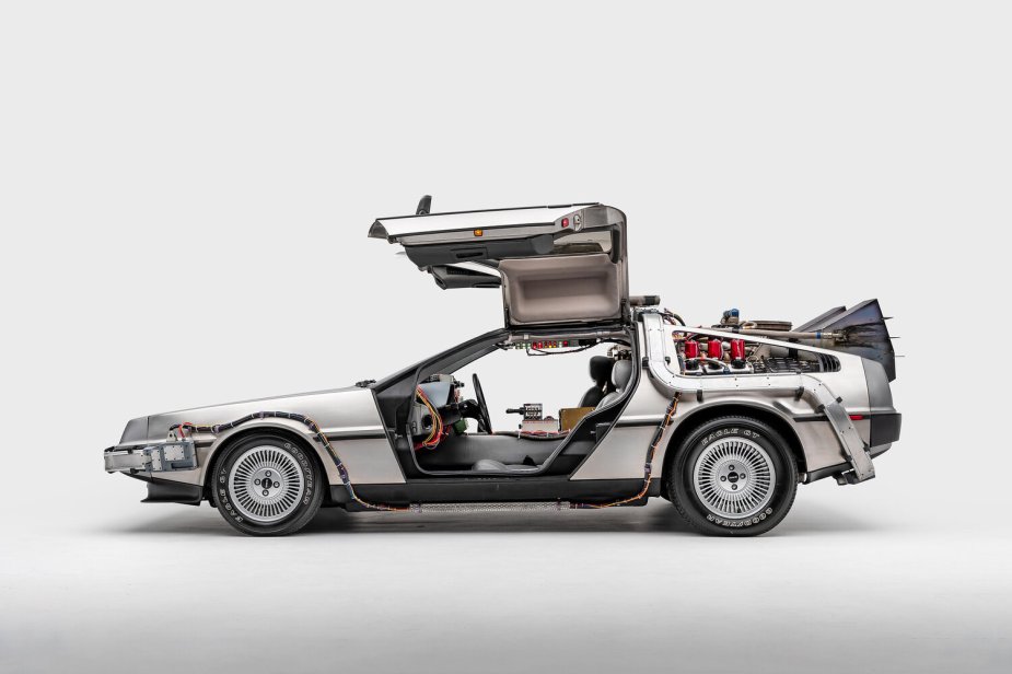 A profile view of the 1981 DeLorean Time Machine from the movie Back to the Future. Car is displayed in a white studio background with the doors open.