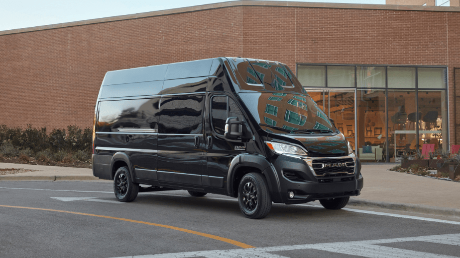 Black 2023 Ram ProMaster parked near a large building, highlighting its release date and price