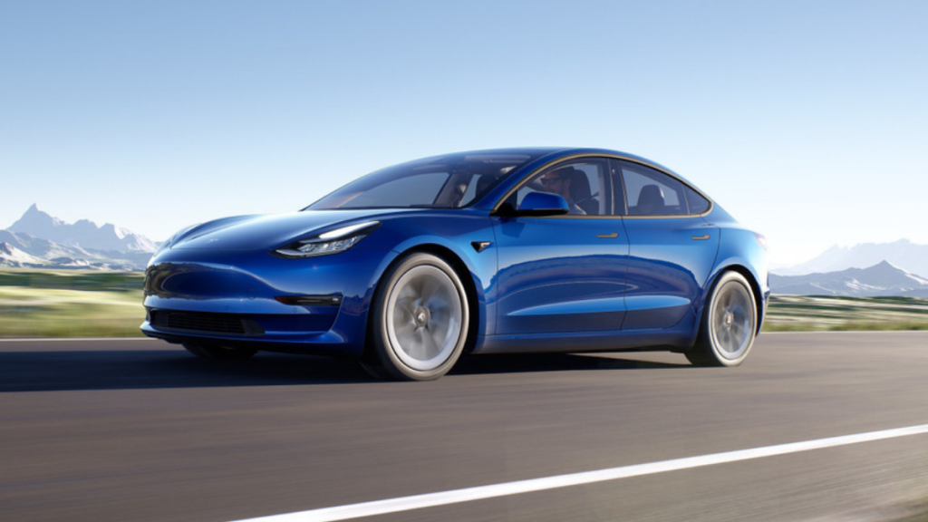 Blue 2022 Tesla Model 3 electric sedan, one of the safest luxury cars to buy in 2022, driving by mountains
