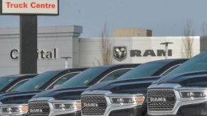 Row of fifth generation Ram trucks parked in front of an old "Dodge Truck Centre" sign at a dealership