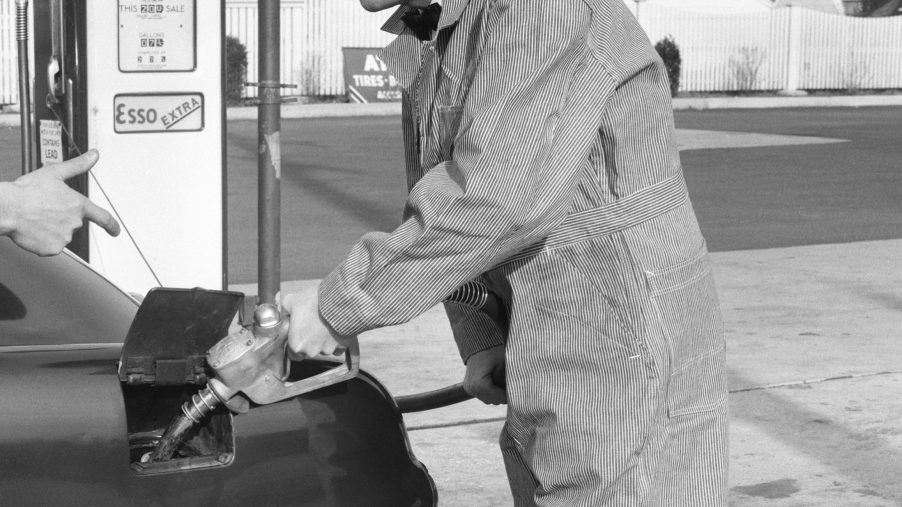gas station attendant fills up gas tank in black and white