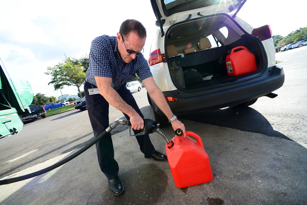 A Florida resident safely fills gas cans at a station away from their white SUV