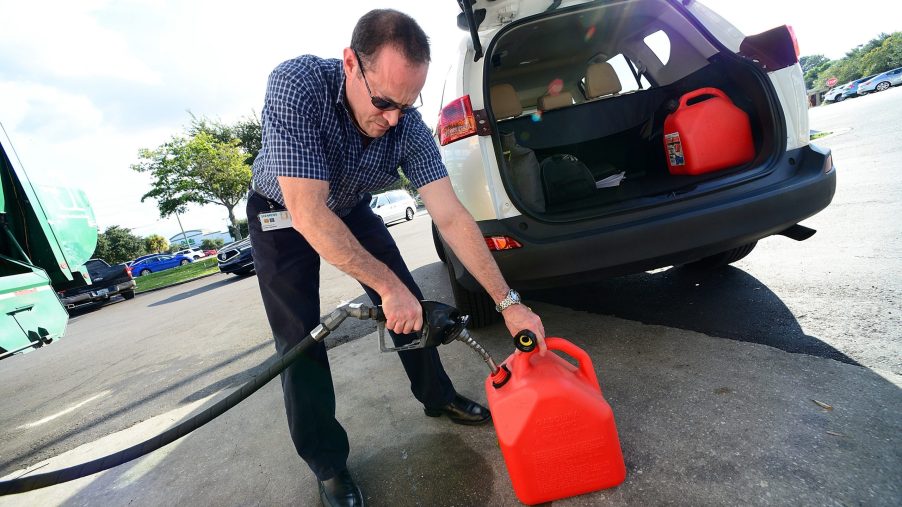 A Florida resident safely fills gas cans at a station away from their white SUV