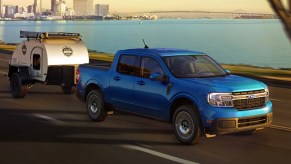 A blue 2022 Ford Maverick midsize pickup truck is towing a small trailer.