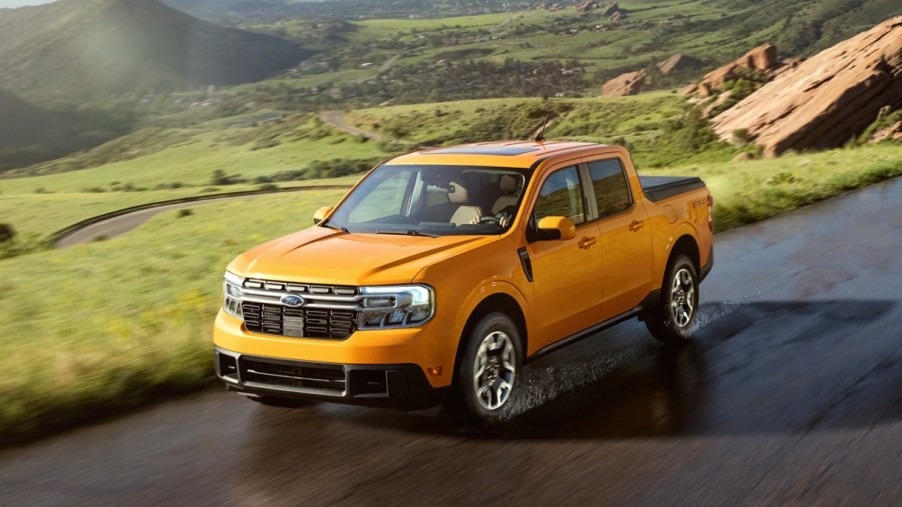 A yellow 2022 Ford Maverick compact pickup truck is driving on a wet road.