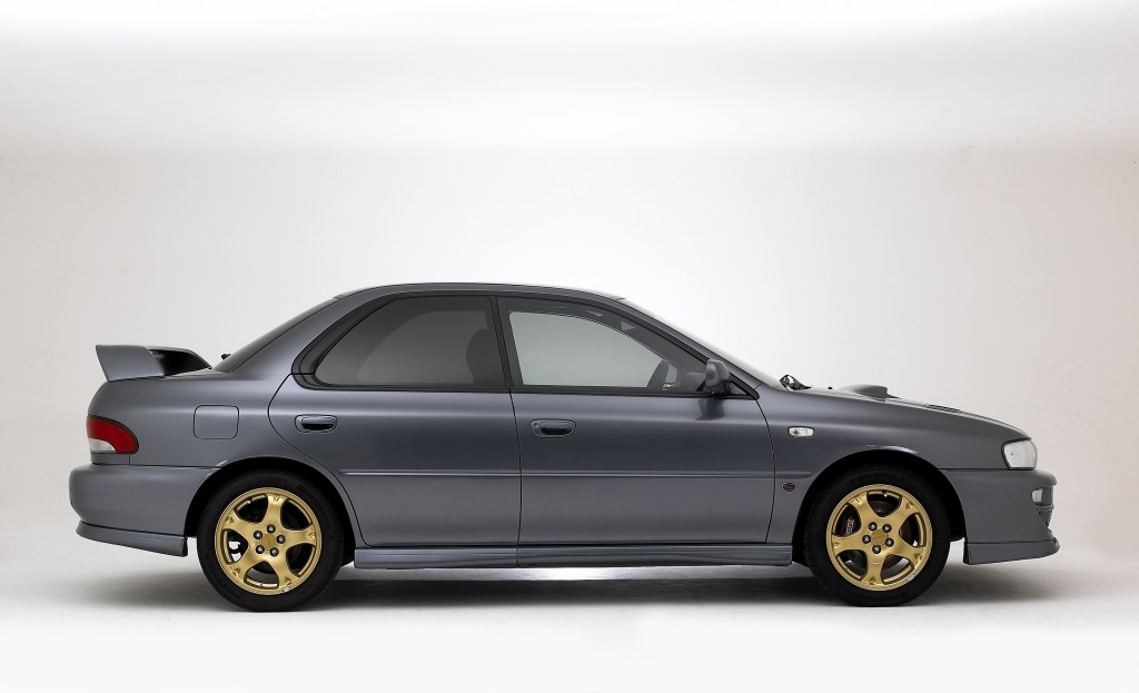 The side view of a gray GC8 Subaru Impreza WRX STi with gold wheels