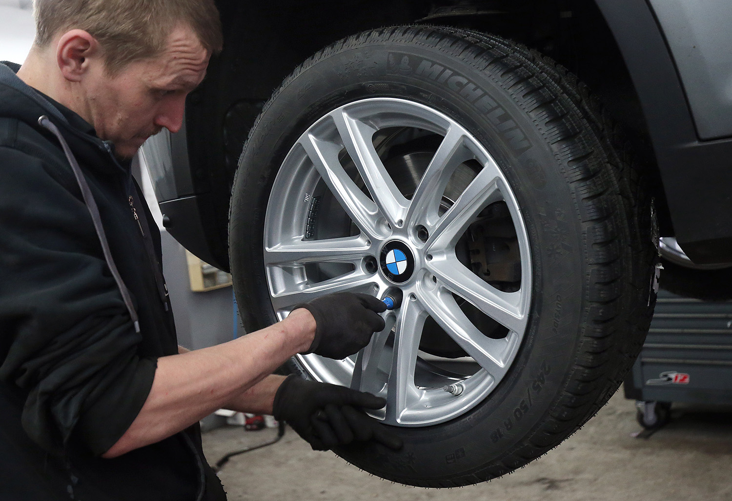 Mechanic Inspecting and Fillling BMW tire with air