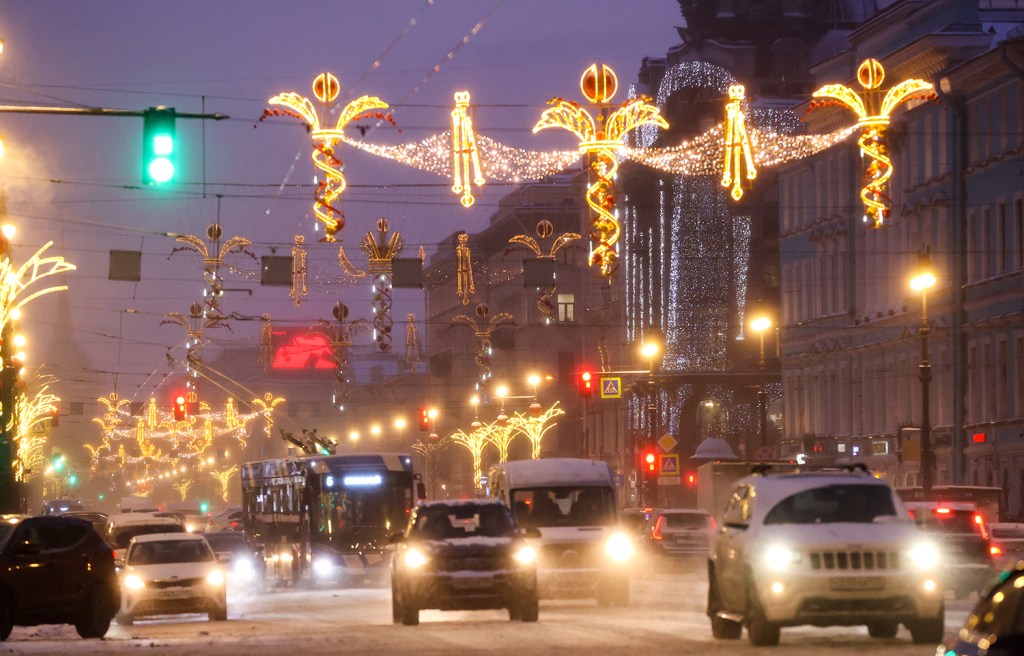 Traffic moving along a Street decorated for the holiday season with Christmas lights.