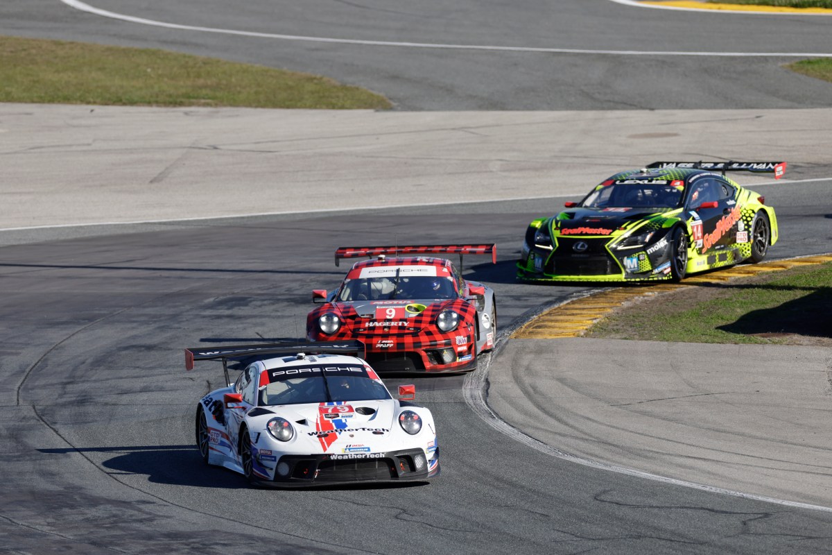 A image of two Porsche GT3R racecars leading a Lexus RC racecar through a corner at the 24 Hours of Daytona race.