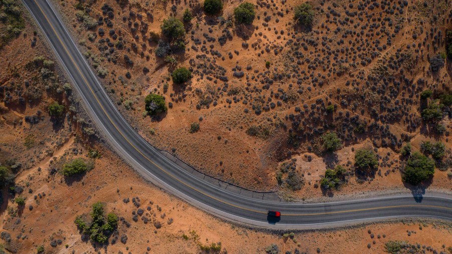 Drone aerial view of winding road and red car in Utah.