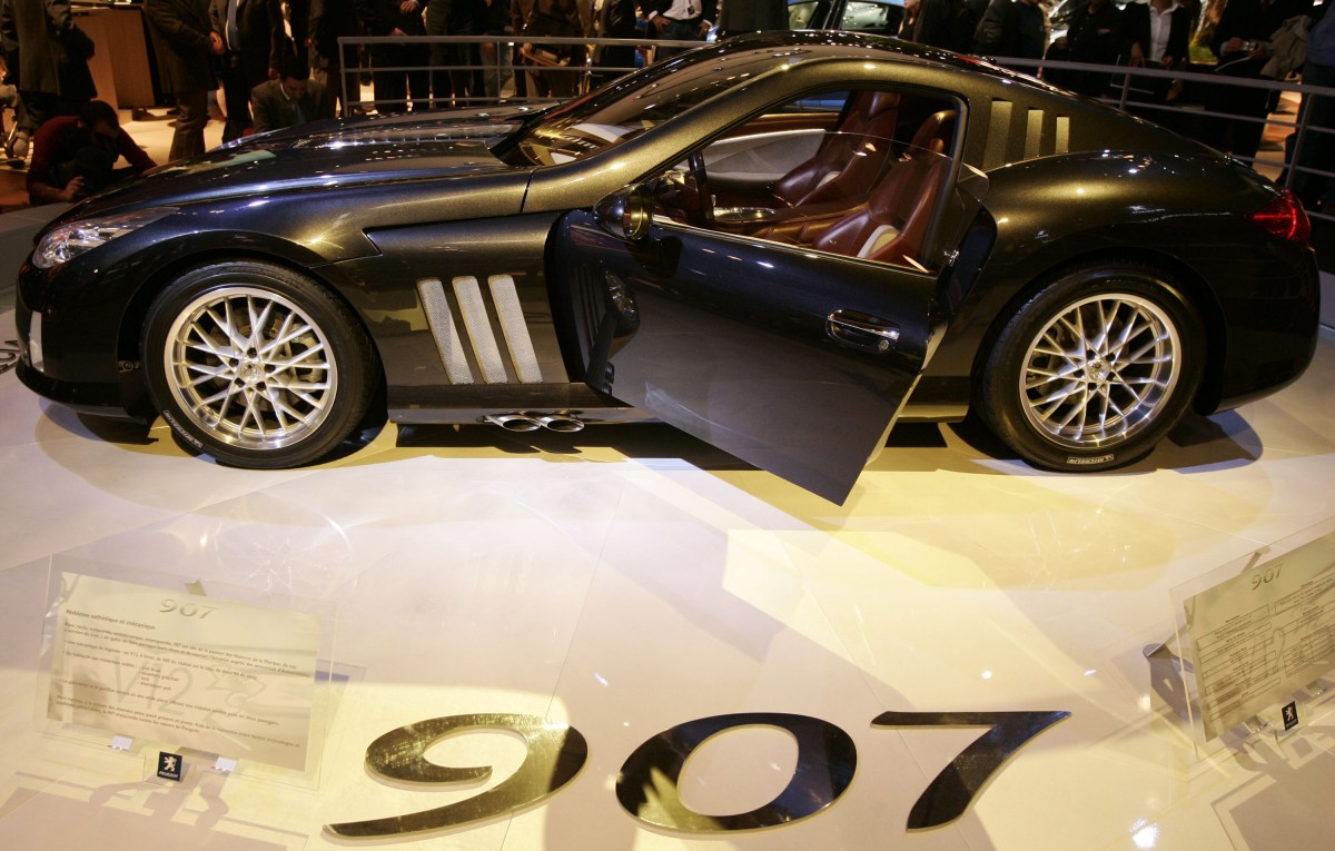 A profile view of a black Peugeot 907 supercar with the drivers door open on display at the Paris Motor Show. 