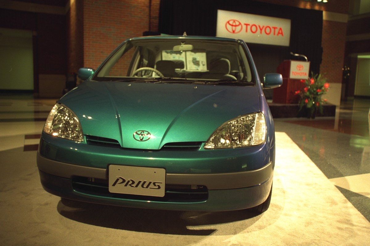 A front view of a green 1998 Toyota Prius parked on an indoor stand at the Detroit Auto Show.